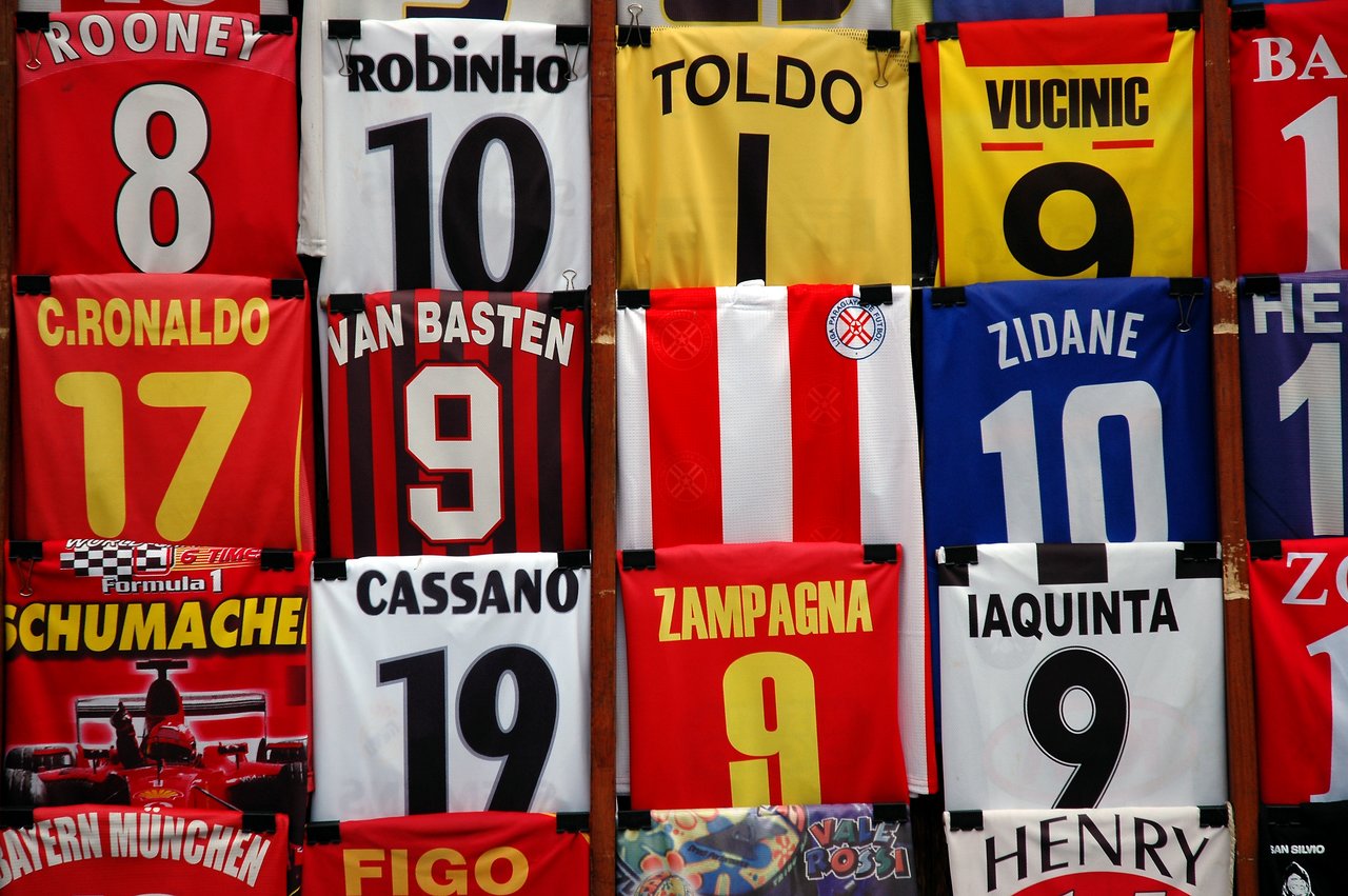 A display of soccer jerseys featuring player names and numbers, arranged on a wooden surface.