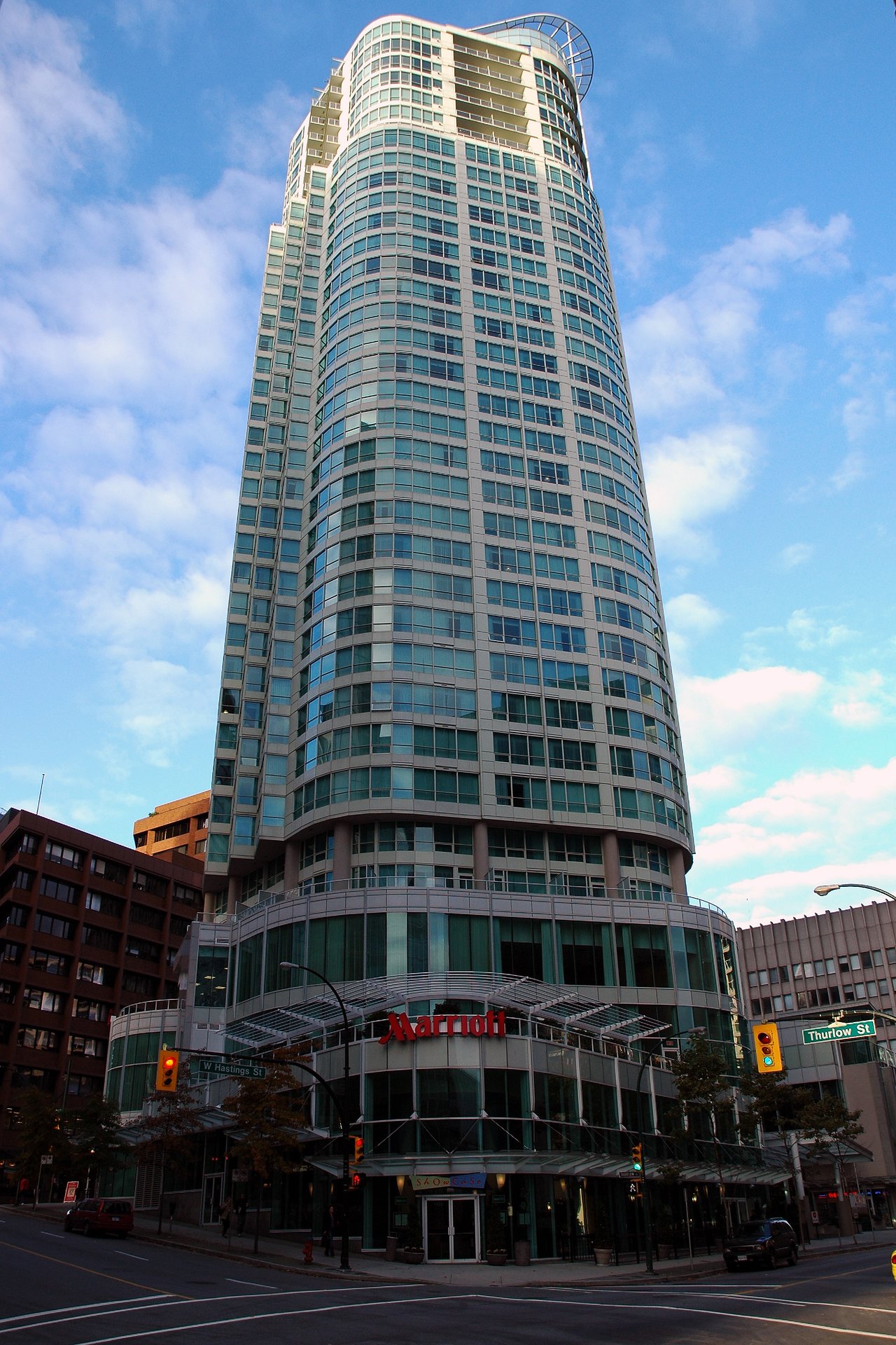Tall glass hotel building with a "Marriott" sign at the entrance, located at a street intersection in Vancouver.