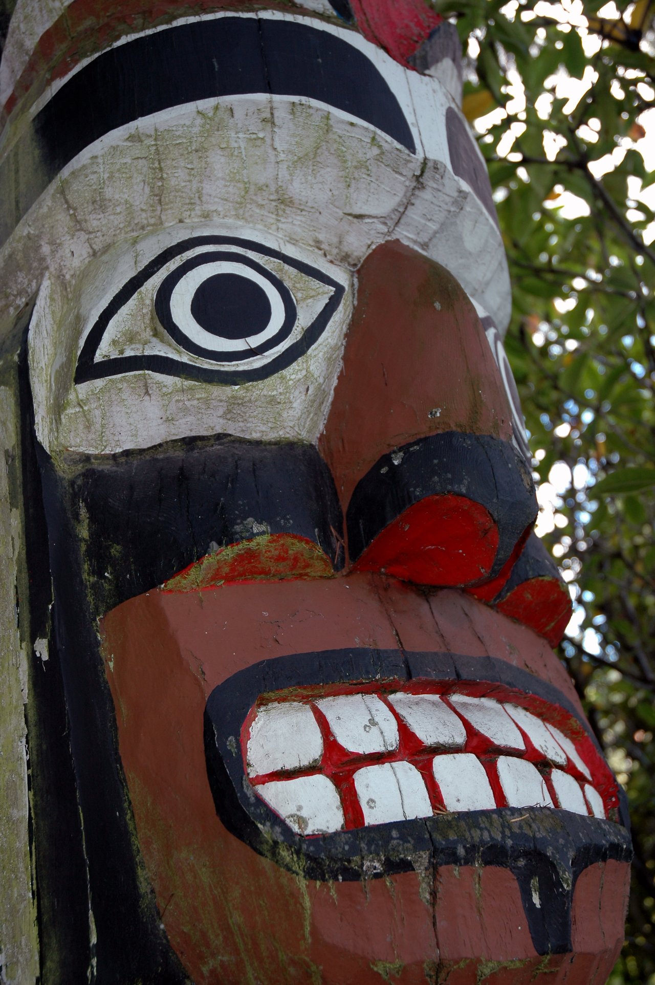 Close-up of a carved and painted Indigenous mask with bold colors, large eyes, and prominent teeth.