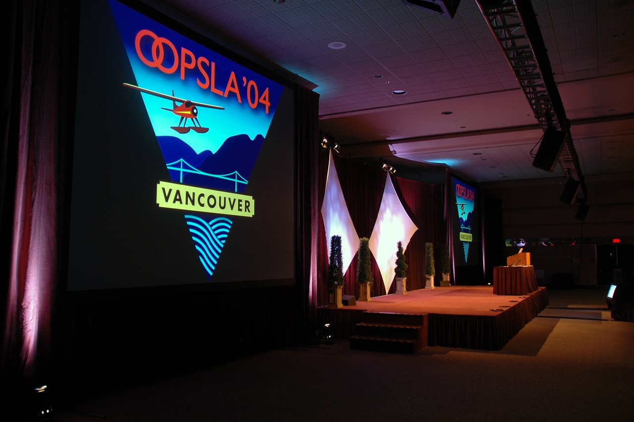 A stage at OOPSLA 2004 in Vancouver with a large screen displaying the event logo and a podium.