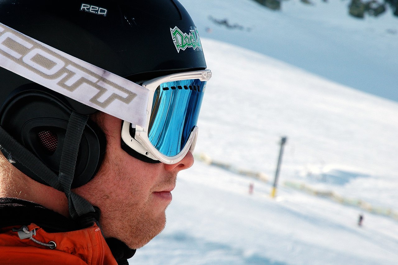 A person wearing a ski helmet and goggles looks out over a snowy mountain landscape.