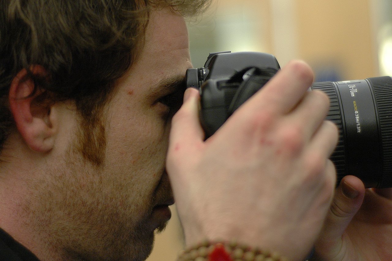 A person holding a camera close to their face, looking through the viewfinder while taking a photo.