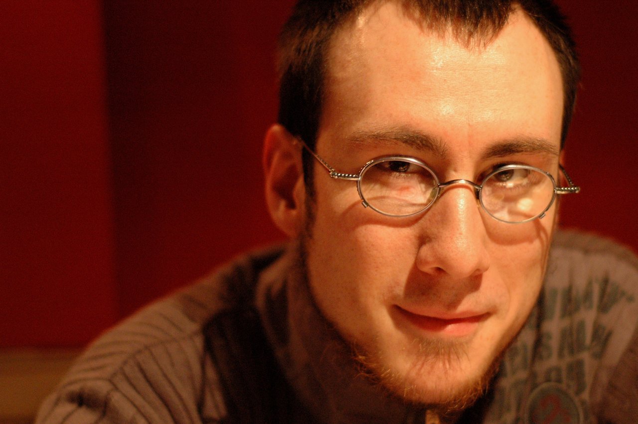 A man with glasses and a short beard looks at the camera with a slight smile.