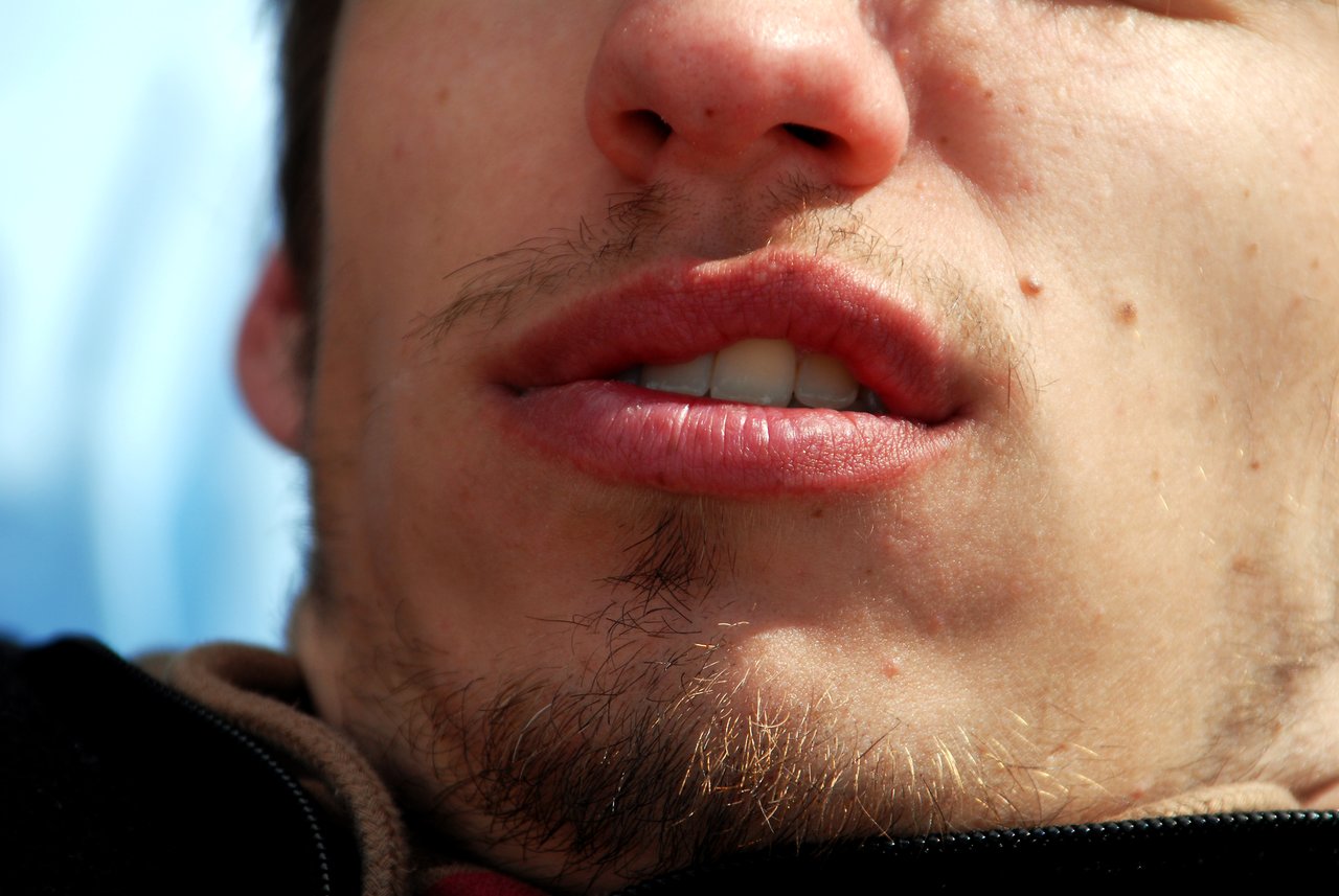 Close-up of a person's lower face, showing lips, chin, and light facial hair.