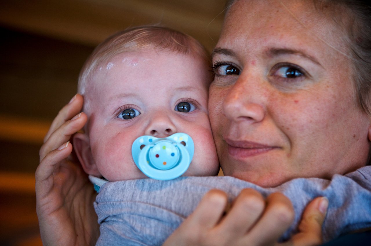 A woman holds a baby close to her face.
