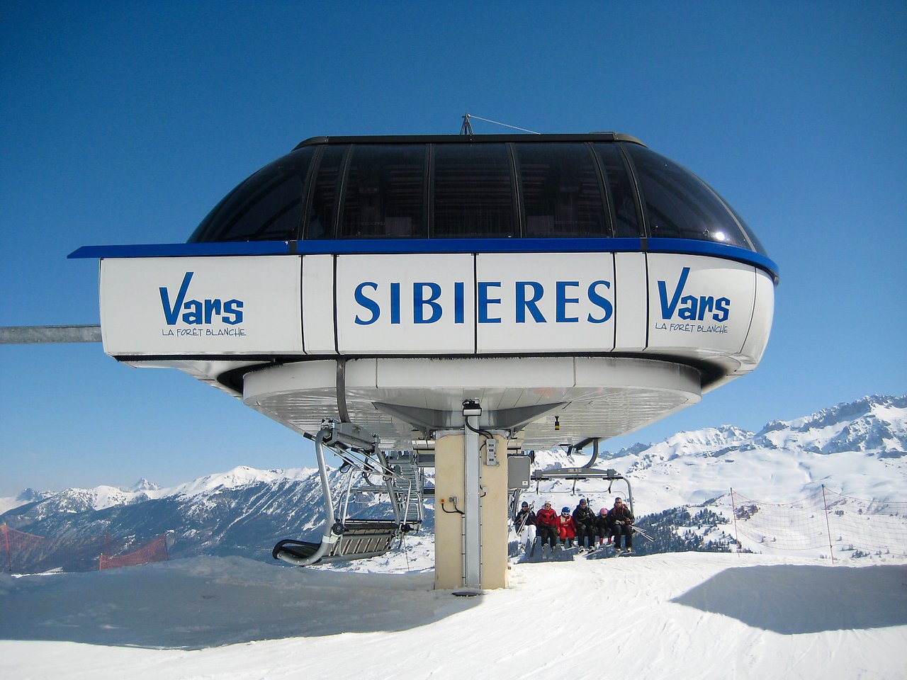 A ski lift station with a group of skiers sitting on a chairlift, preparing to ascend the mountain.
