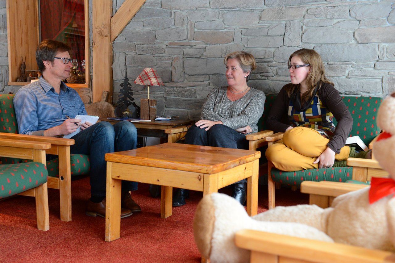 Three people sit in a cozy room, engaged in conversation.
