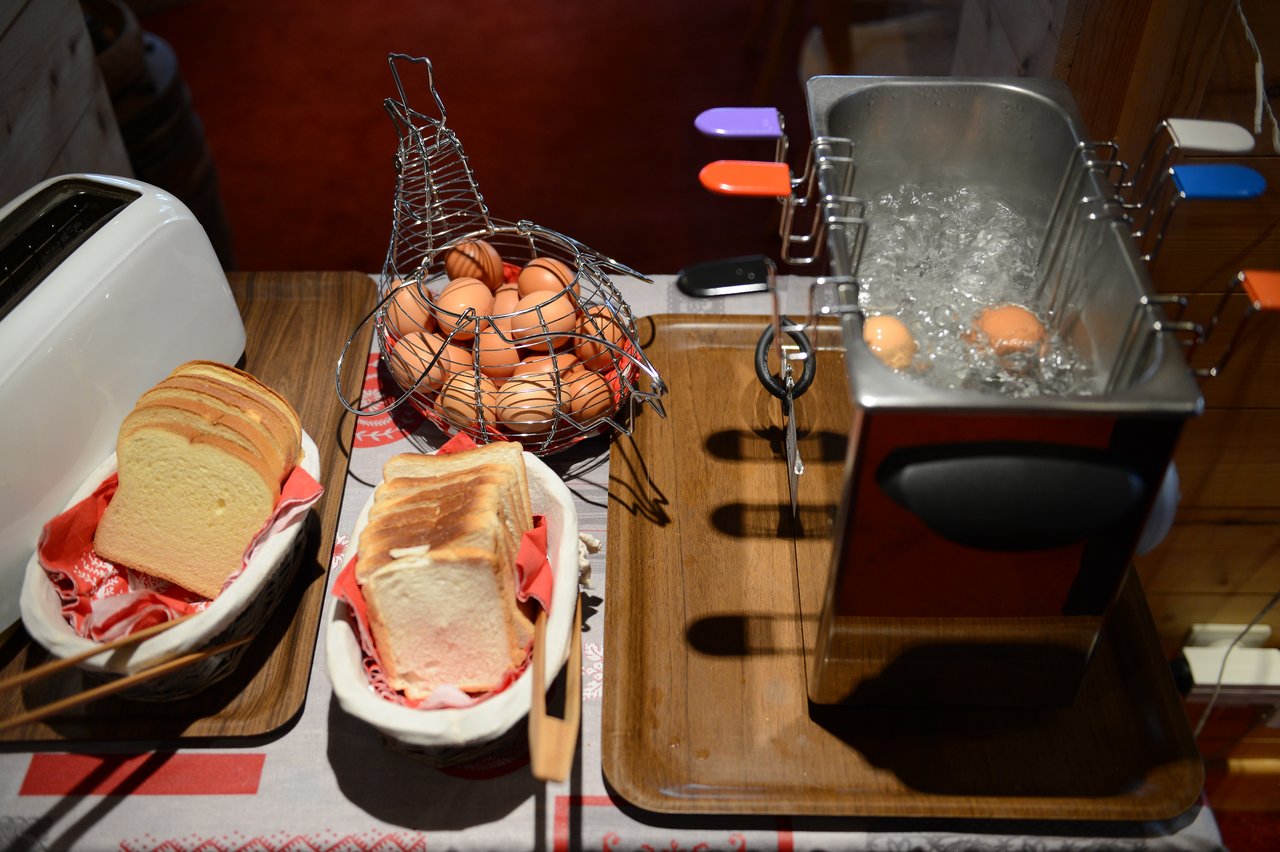 Slices of bread, a toaster, and a basket of eggs next to a boiling egg cooker.