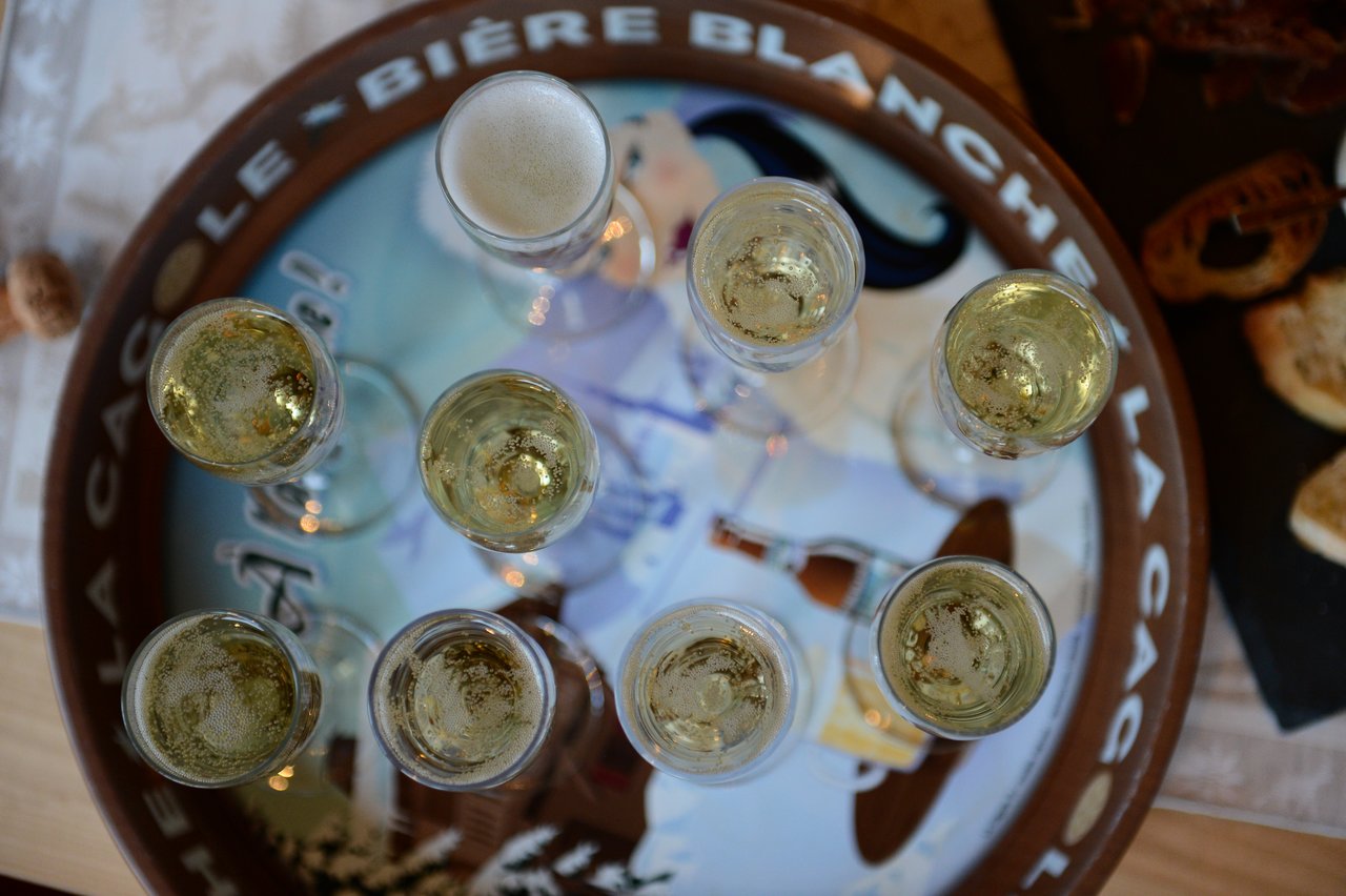 Several glasses of sparkling wine are arranged on a round tray, viewed from above.