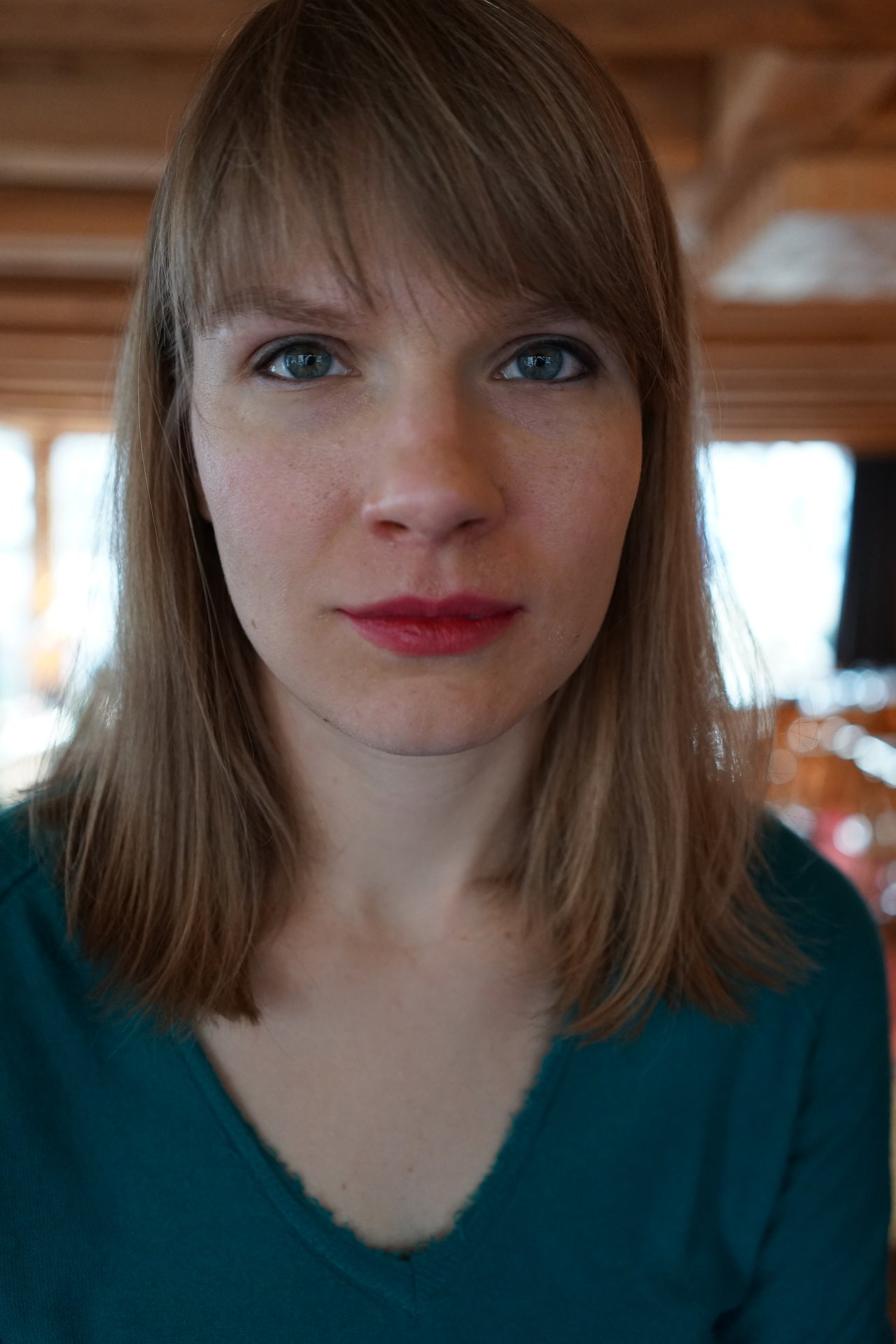 A woman with shoulder-length blonde hair and blue eyes looks directly at the camera with a neutral expression.