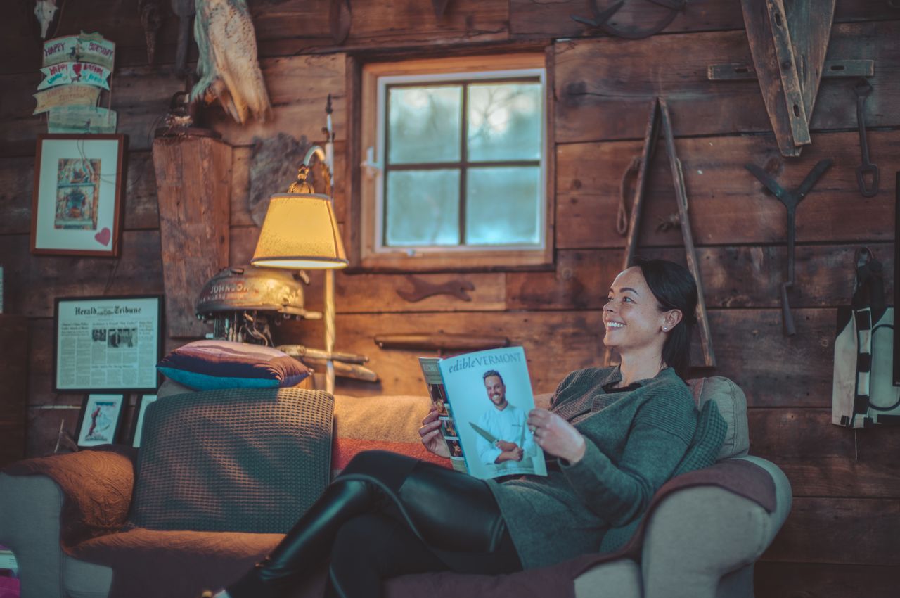 A woman sitting on a sofa reading a magazine.