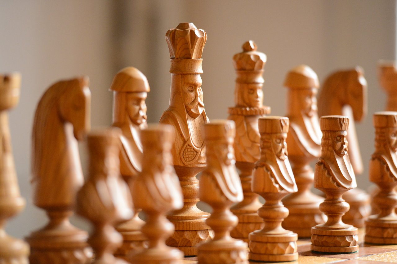 Close-up of a wooden chess set with detailed carved pieces, focusing on the king in the center.