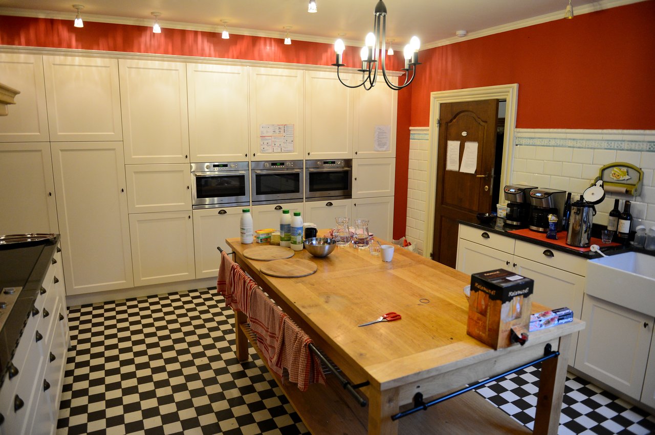 A spacious kitchen with a wooden island, cooking utensils, and drinks set up for a family gathering.
