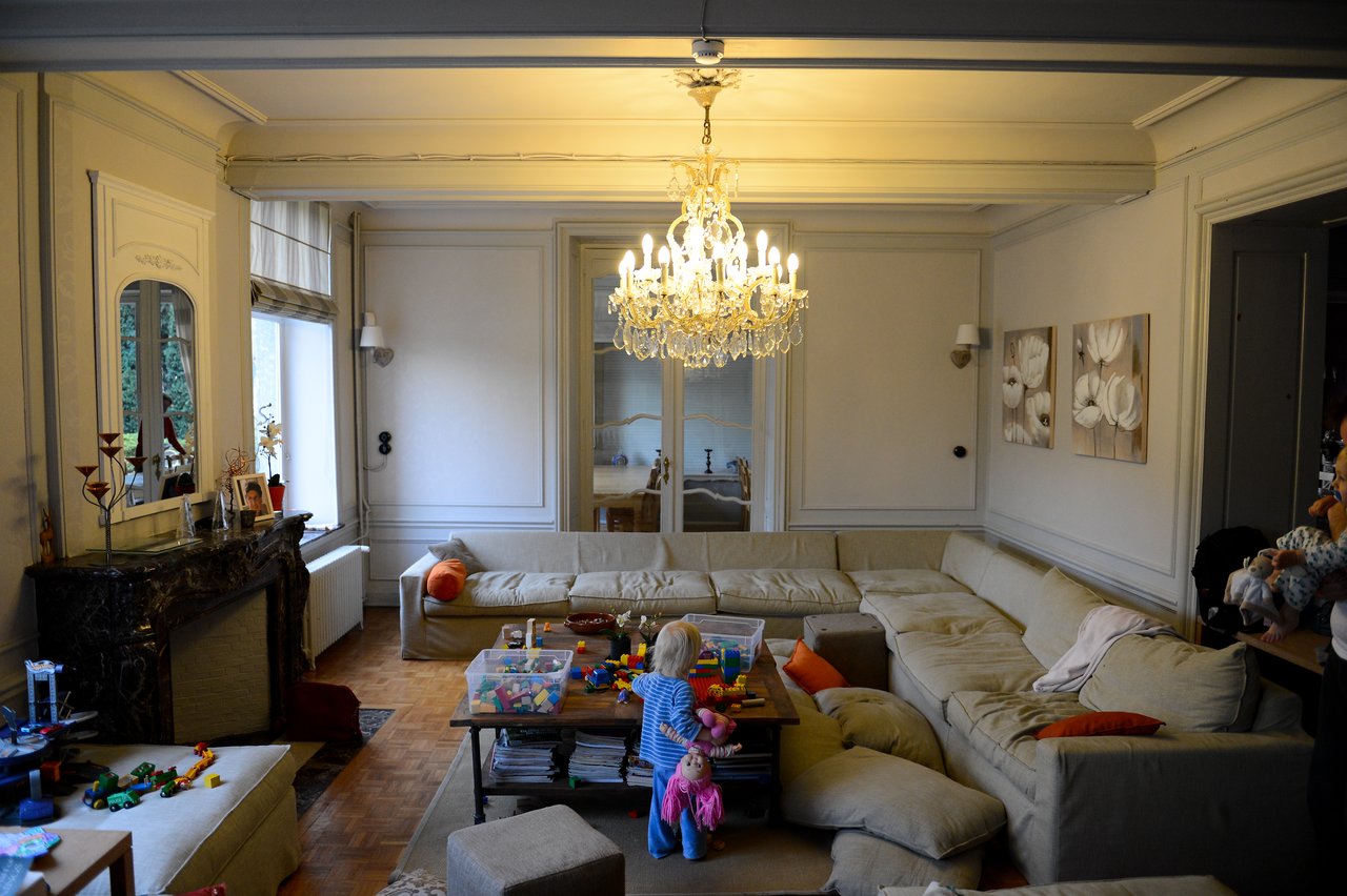 A child plays with toys on a coffee table in a cozy living room with a large sectional sofa.