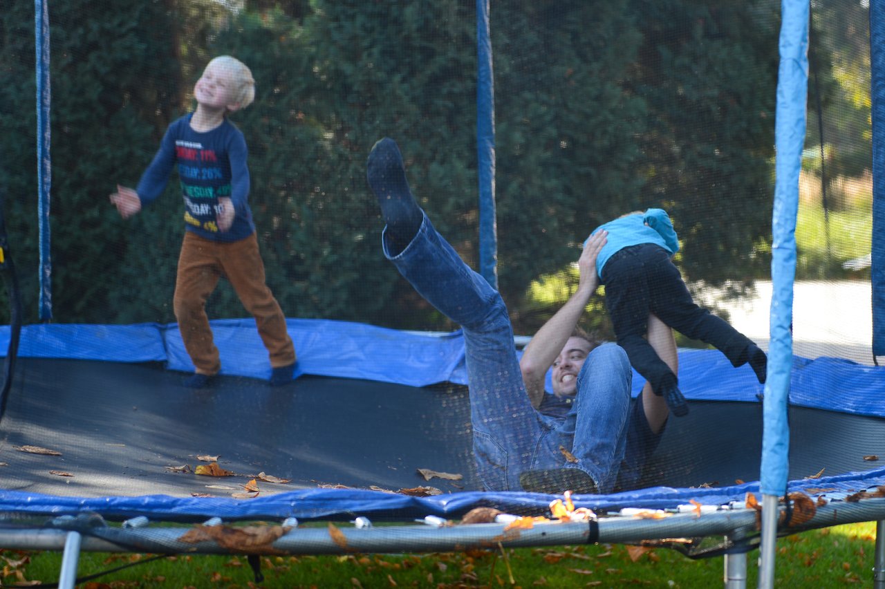 A man and two children play on a trampoline.