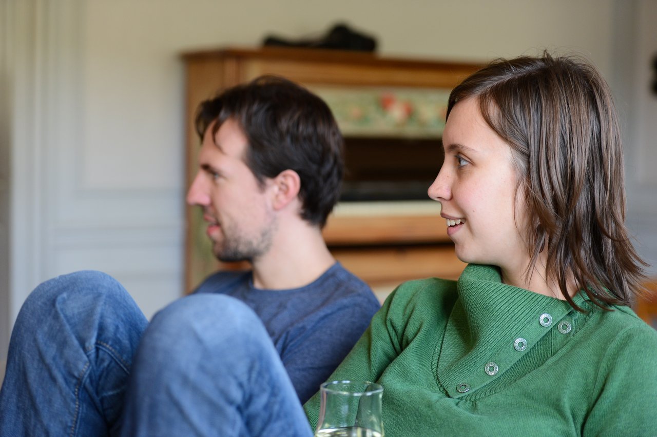 Two people sitting indoors, engaged in conversation.