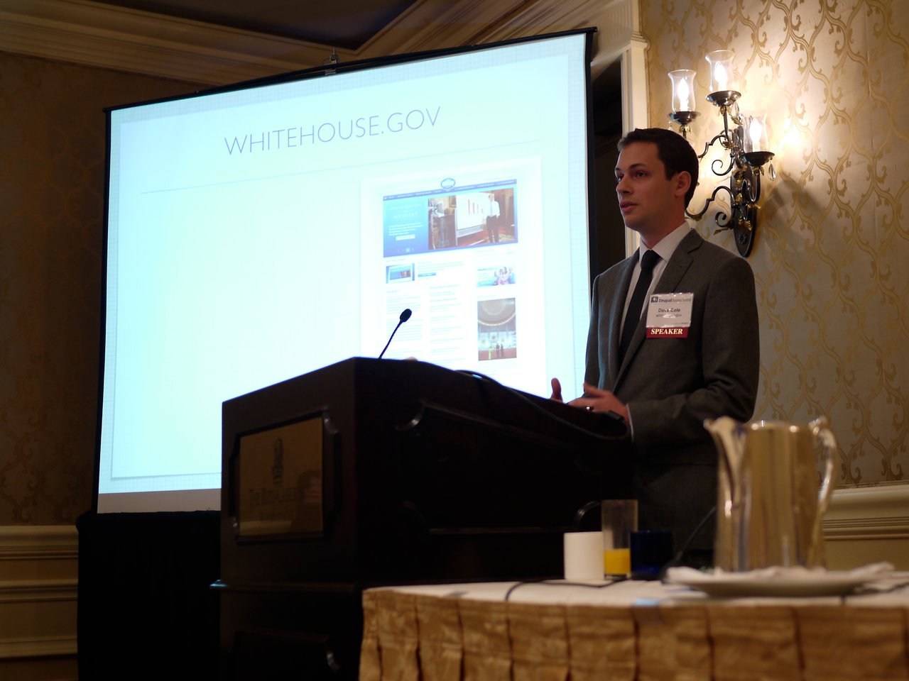A speaker in a suit presents a slideshow about Whitehouse.
