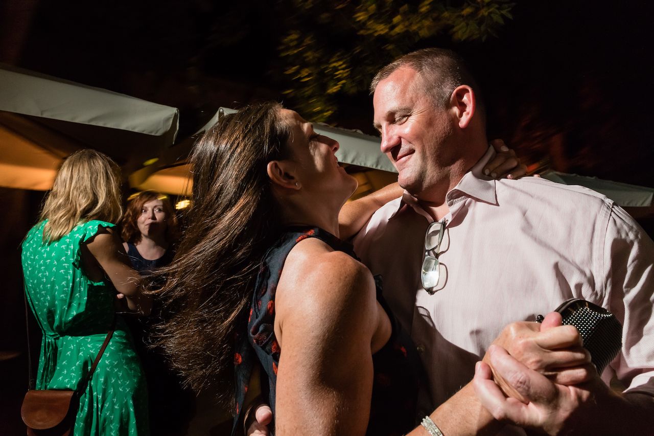 A couple dances closely at a wedding reception, smiling at each other.
