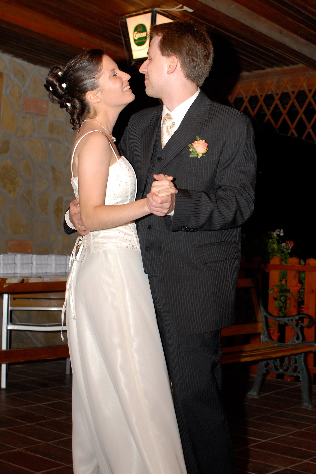 A bride and groom share their first dance, smiling and holding hands at their wedding reception.