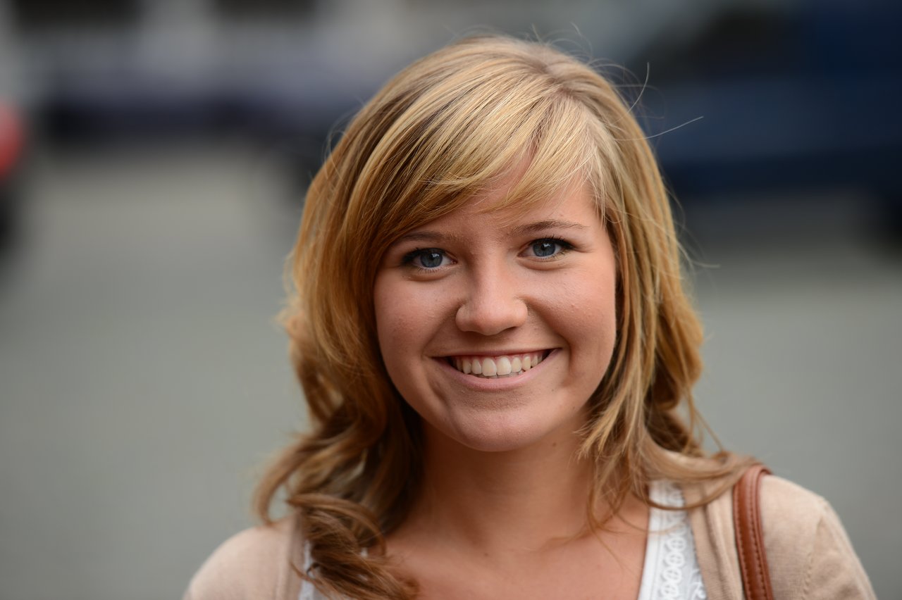 A woman smiling at the camera, outdoors.