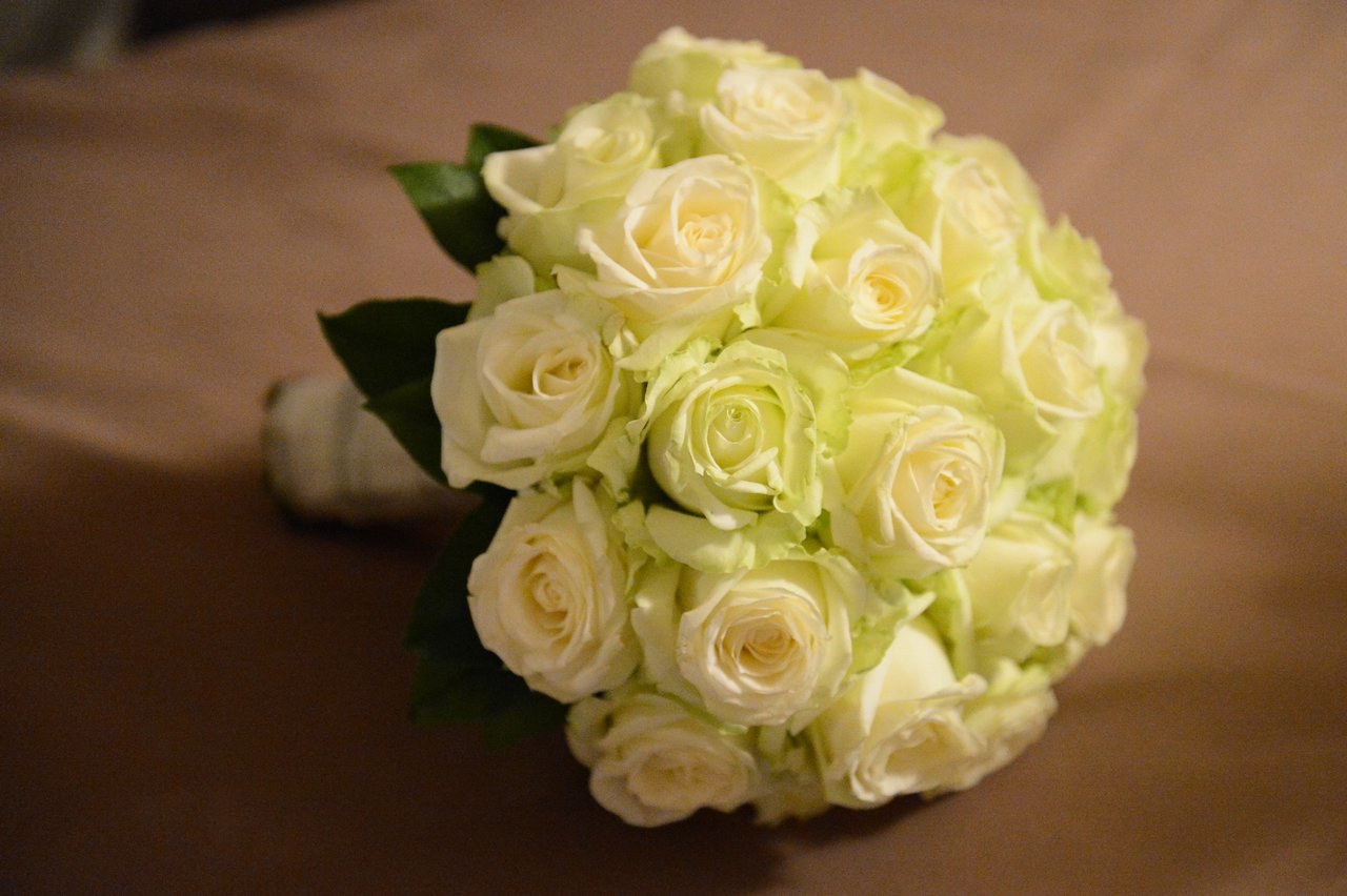 A bridal bouquet of white roses rests on a table.