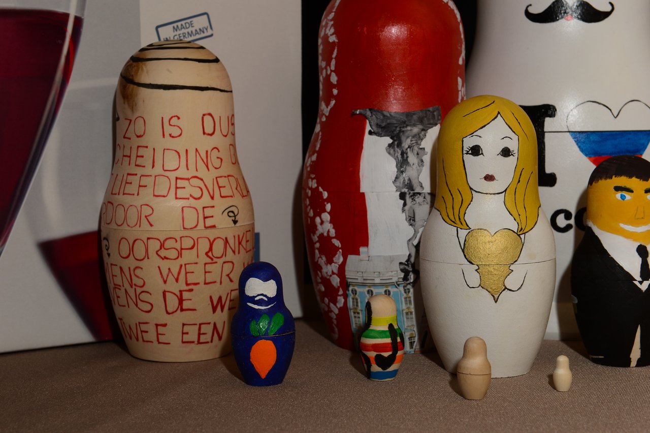 A collection of decorated nesting dolls, including a bride and groom, displayed on a table.