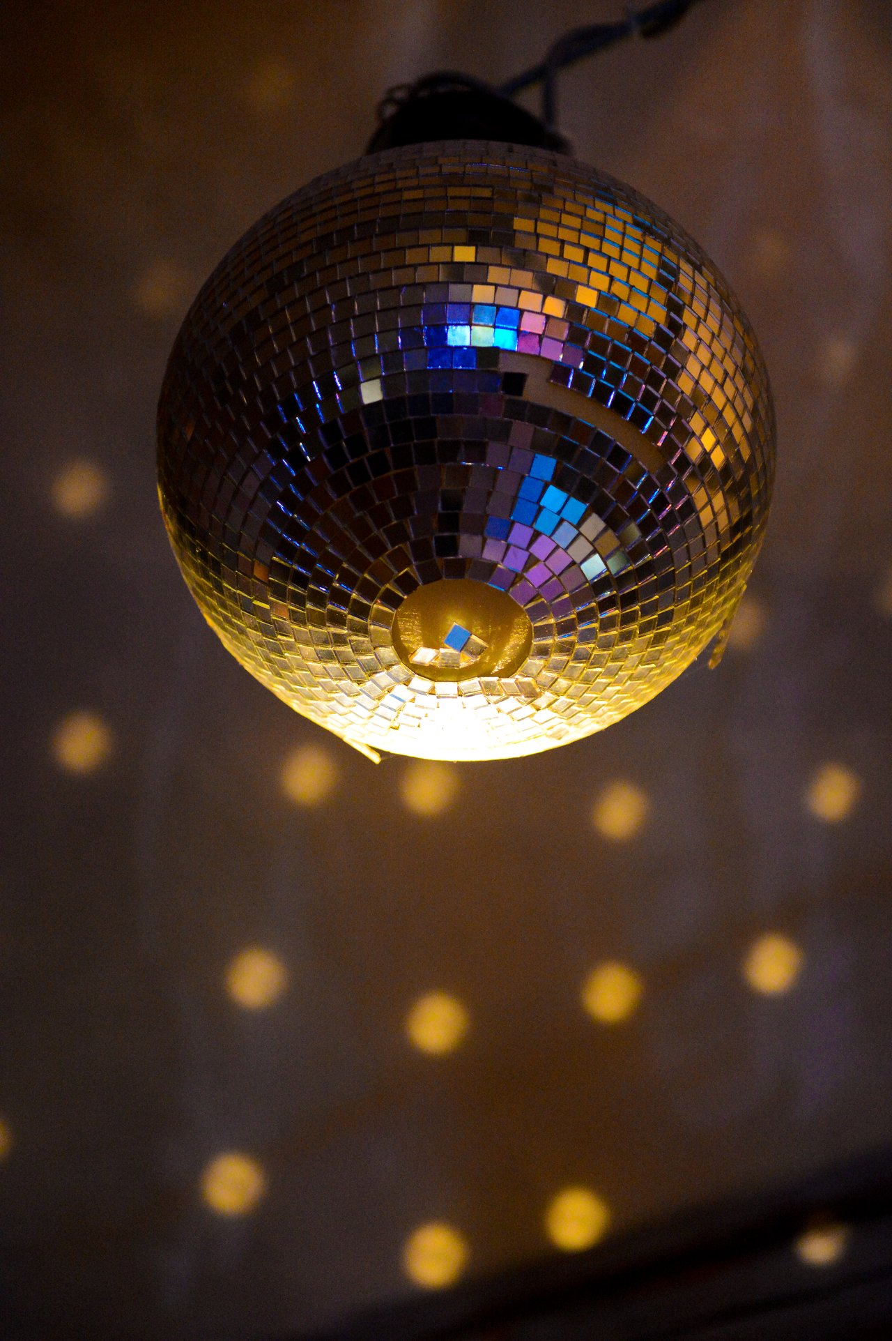 A disco ball hangs from the ceiling, reflecting light and creating a pattern of glowing dots on the wall.