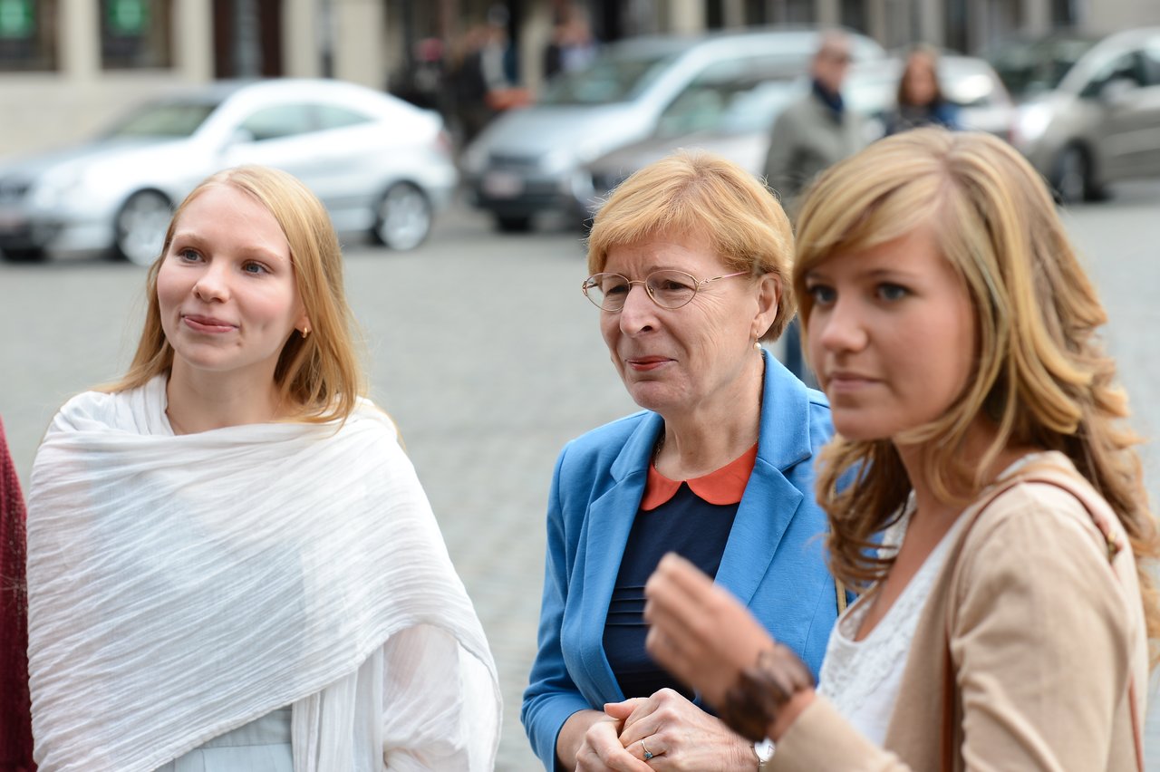 Three women stand together outdoors, engaged in conversation during a wedding event.