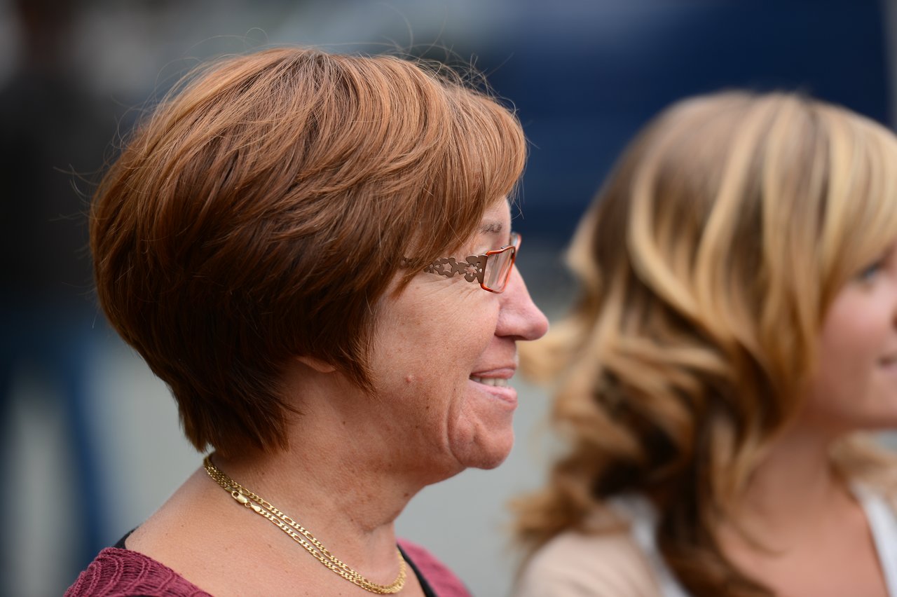 Two women standing side by side, smiling and looking in the same direction at a wedding event.
