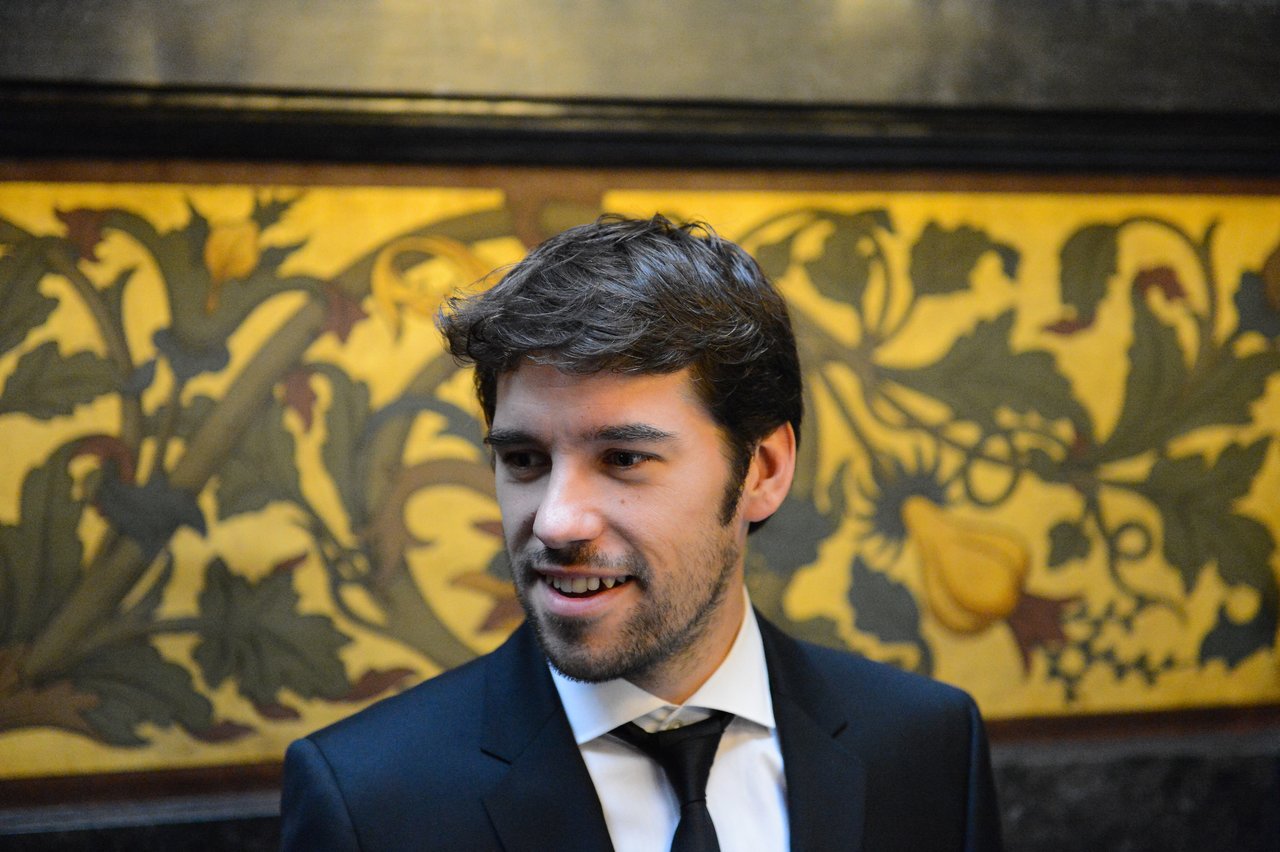 A man in a suit and tie smiles while looking to the side at a wedding event.