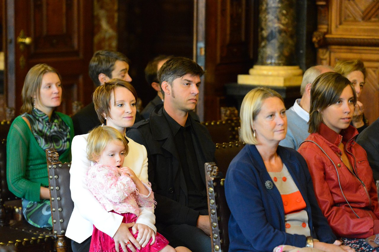 Guests seated in a formal setting, attentively watching the wedding ceremony.