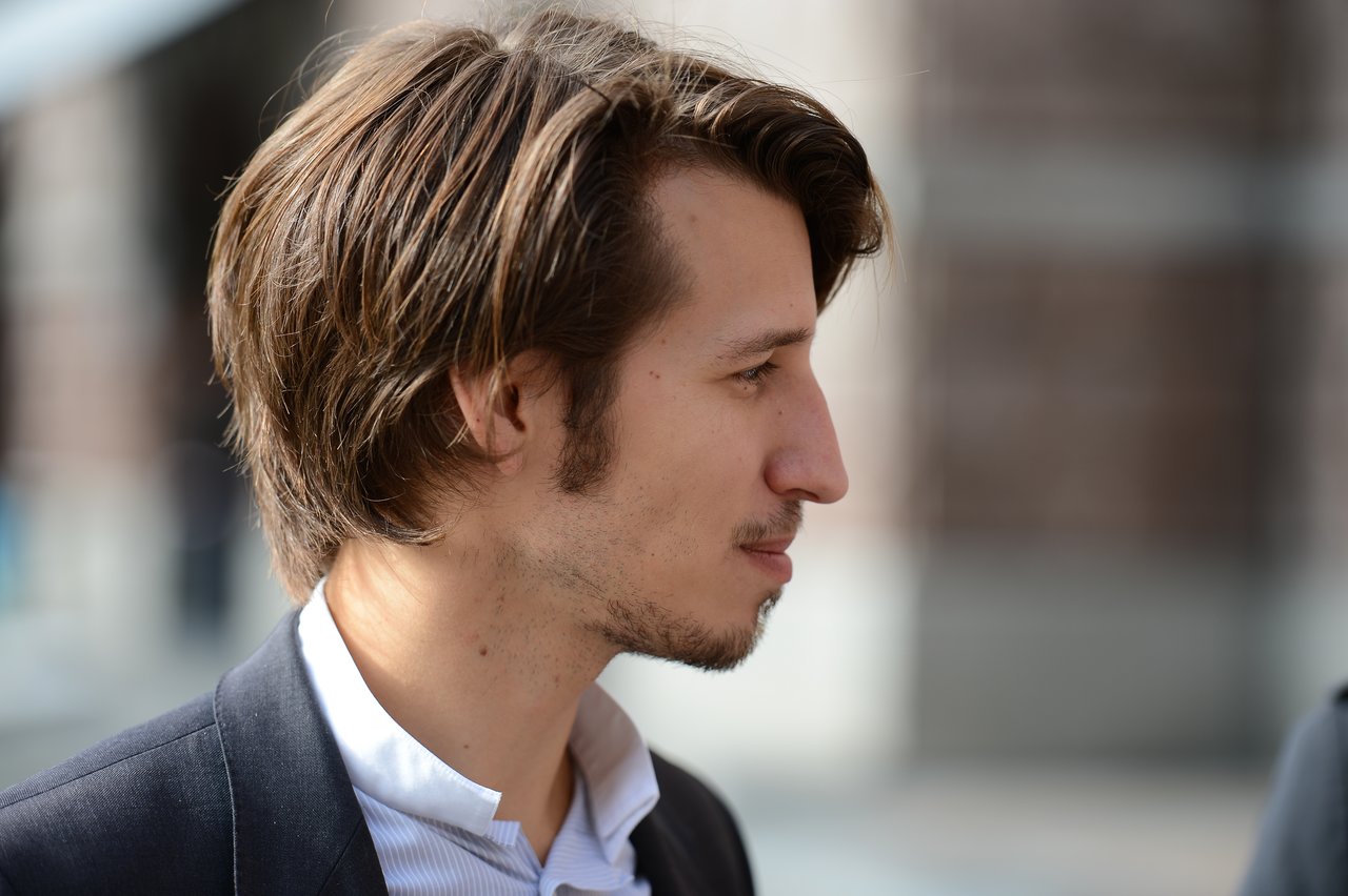 A man in a suit looks to the side during an outdoor wedding event.