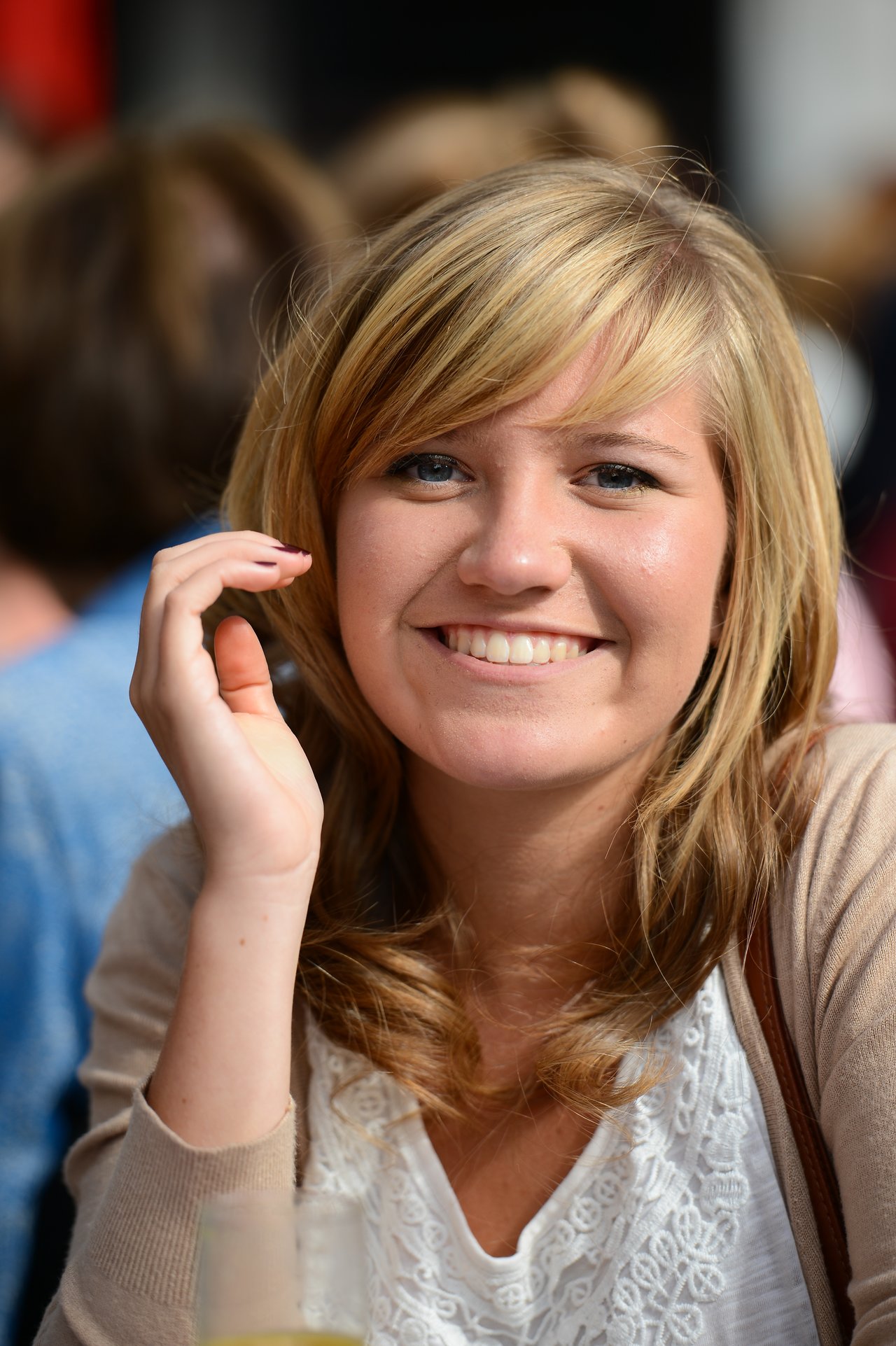A woman with blonde hair smiles at the camera while sitting at a wedding reception.