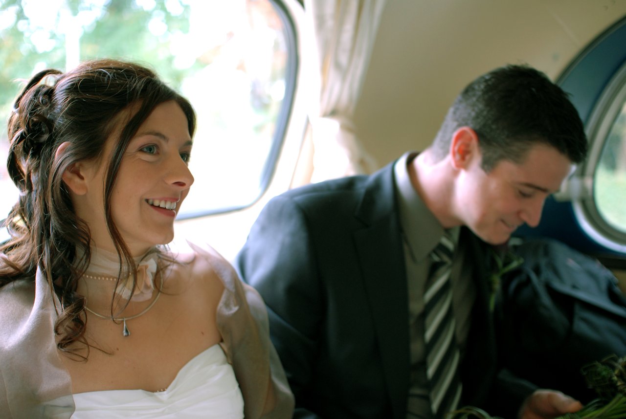 A bride and groom sit together in a vehicle.