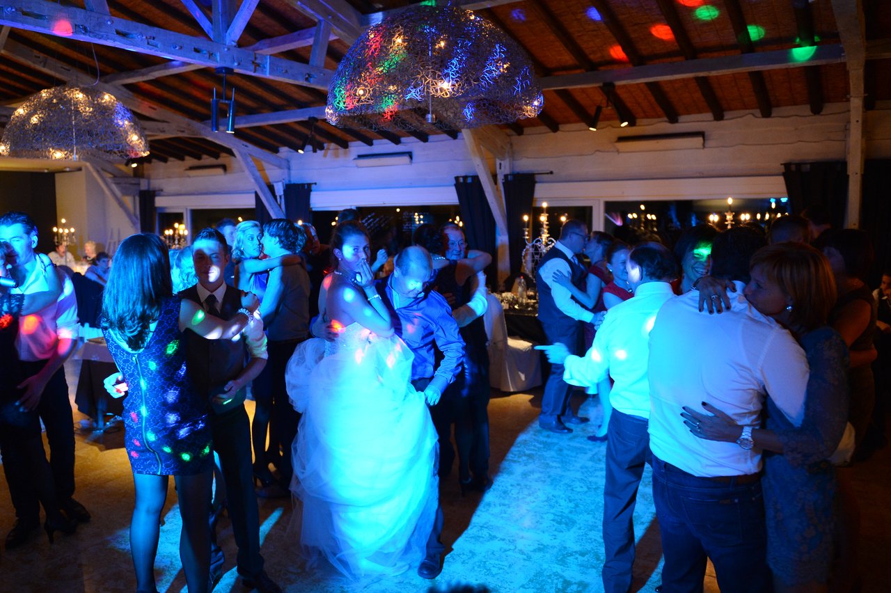 Bride and groom dancing among guests at a wedding reception, surrounded by couples enjoying the celebration.
