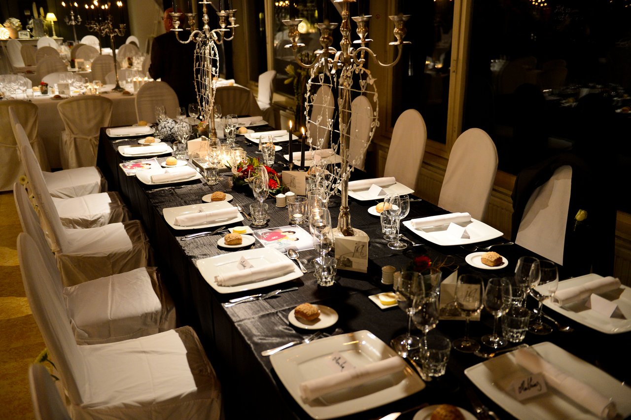 A wedding reception table set with plates, glasses, candles, and decorations, ready for guests to arrive.