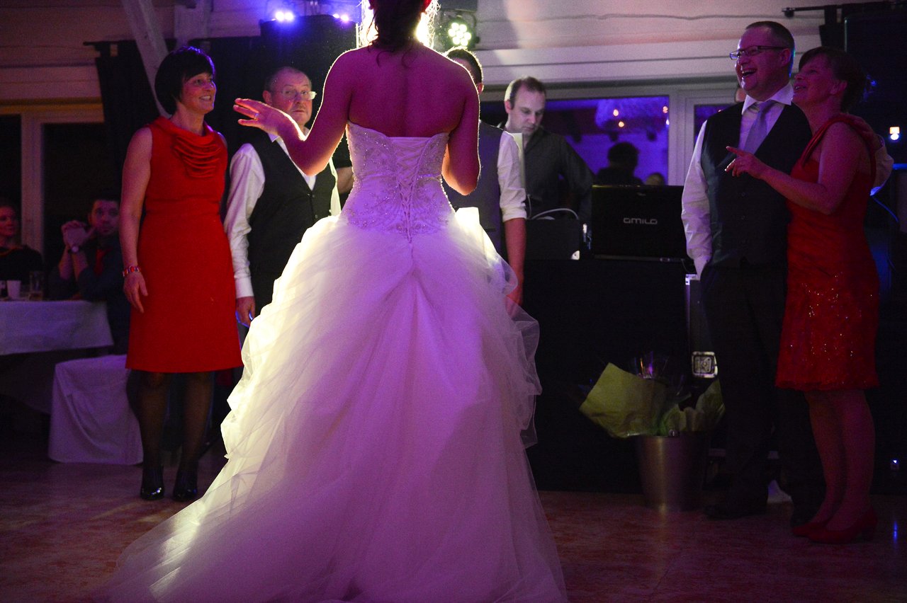A bride in a white gown dances and interacts with guests at a wedding reception.
