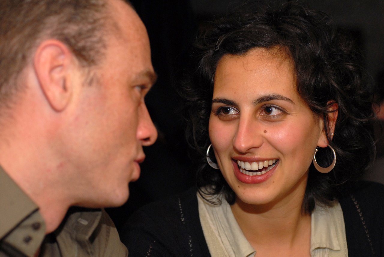 A man and woman are talking at a wedding reception.