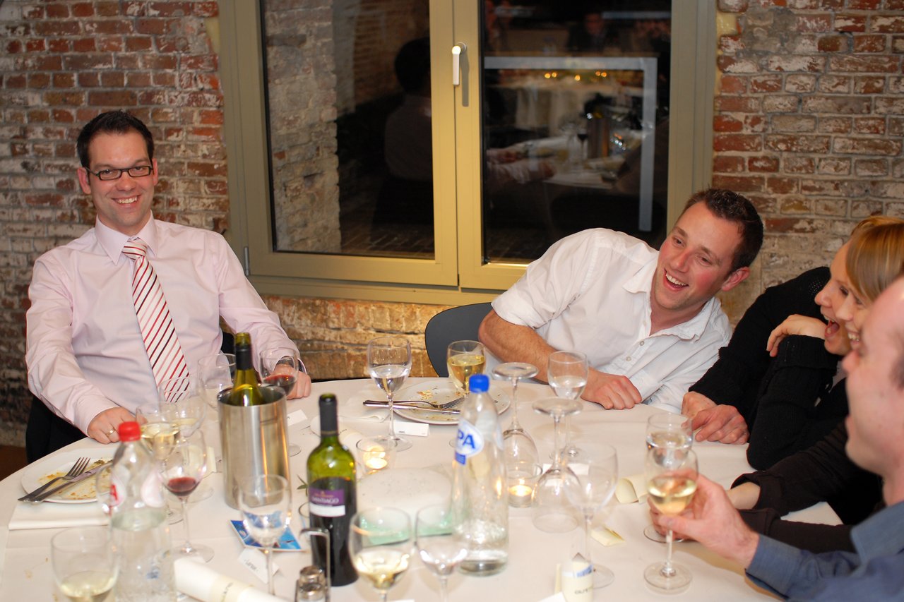 Guests sitting at a table, laughing and enjoying drinks during a wedding celebration.