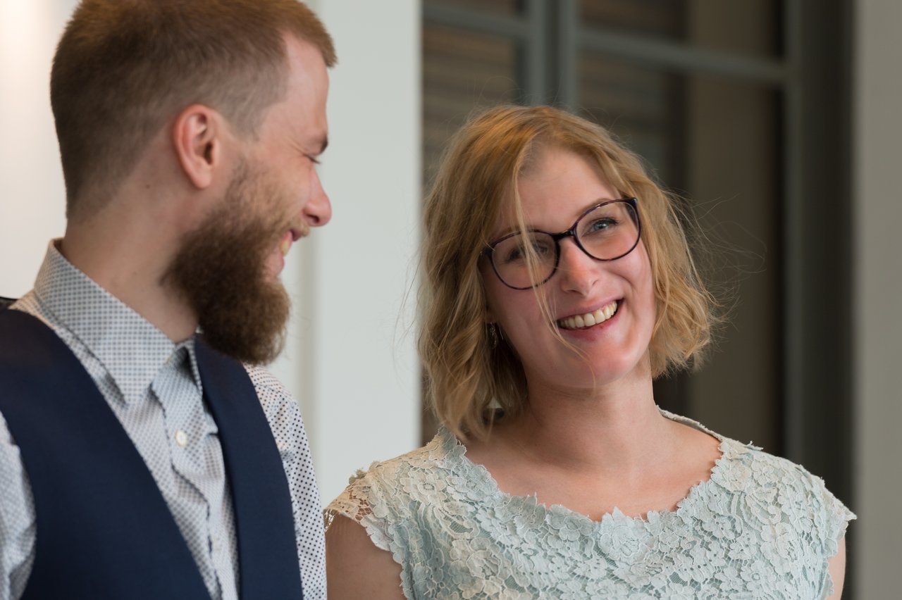 A smiling couple looks at each other on their wedding day, dressed in formal attire.