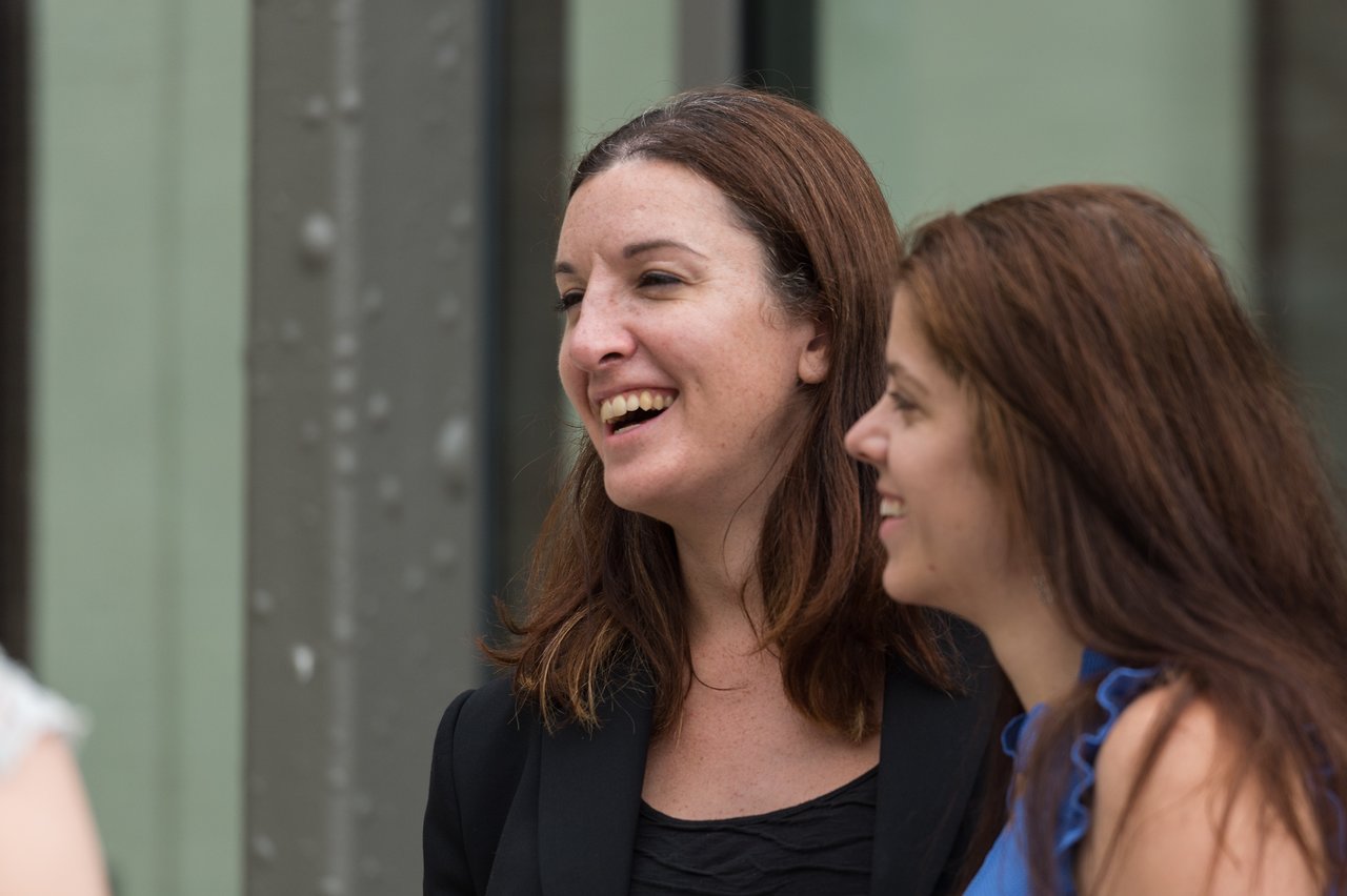Two women smiling and talking at a wedding celebration.