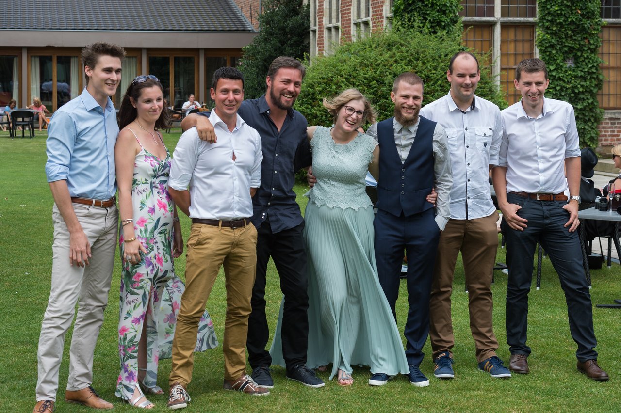 A group of eight people posing together at a wedding, with the bride and groom in the center, smiling.