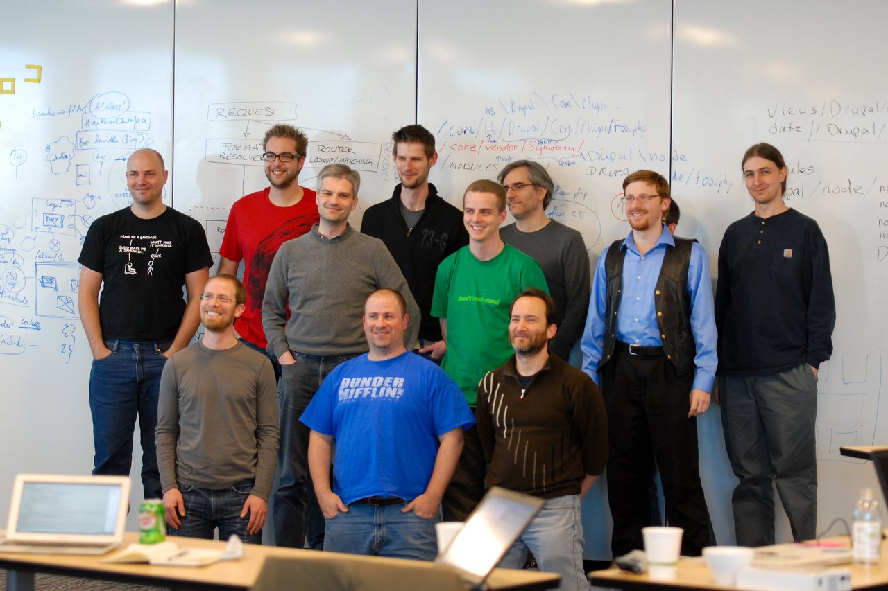 A group of people poses in front of a whiteboard filled with notes and diagrams during a work sprint.