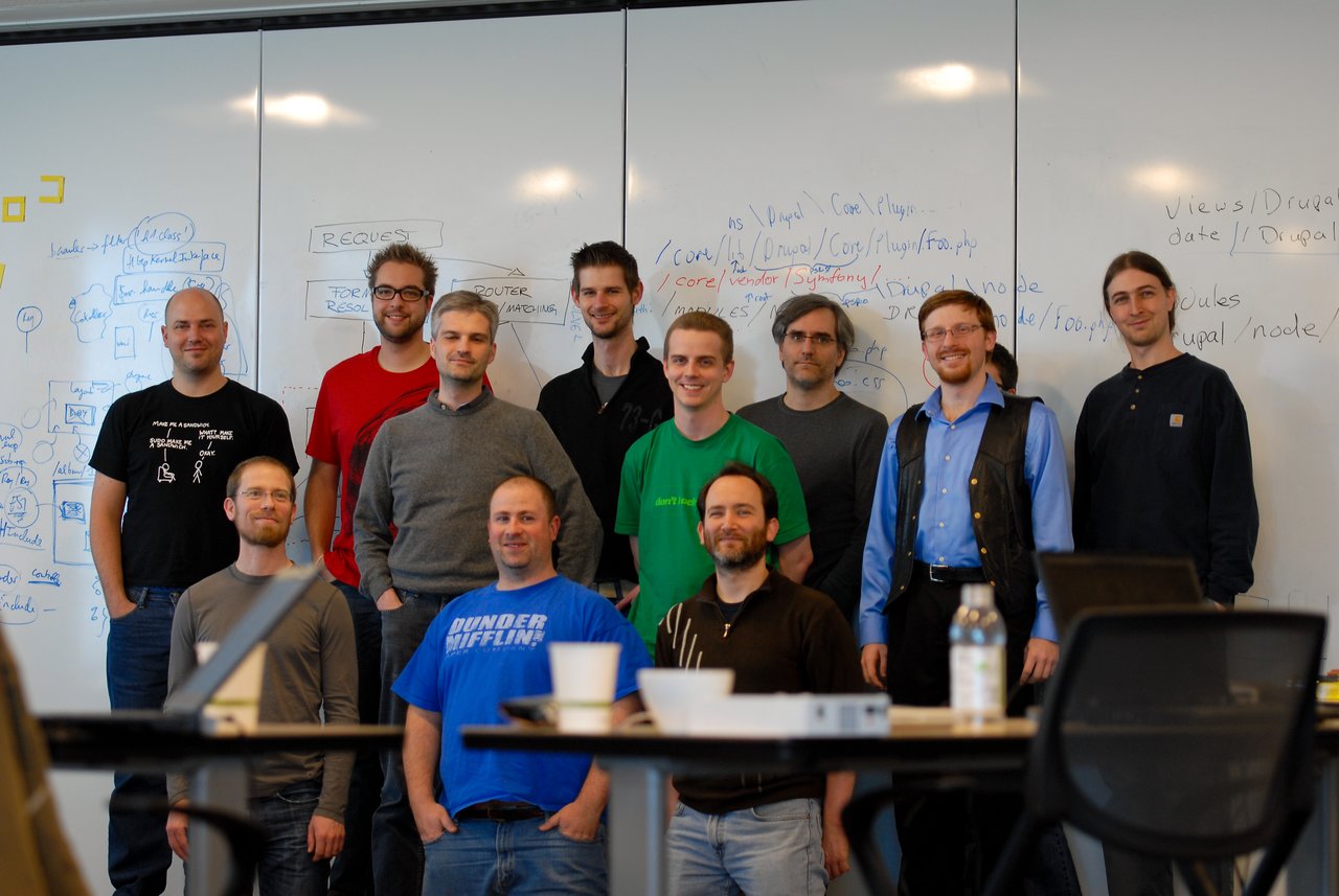 A group of people poses in front of a whiteboard filled with notes and diagrams during a work sprint.