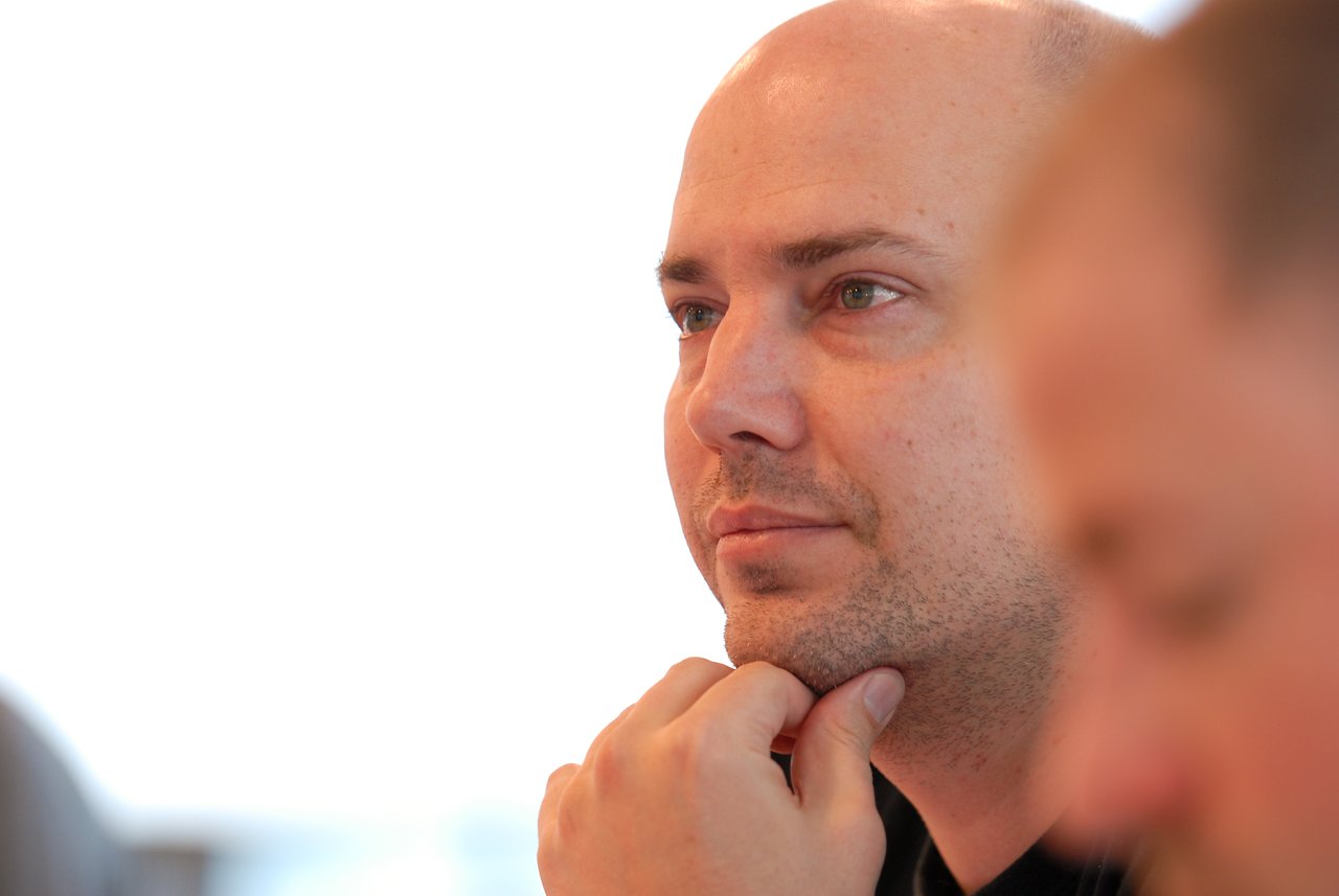 A man rests his chin on his hand, appearing focused during a discussion or meeting.