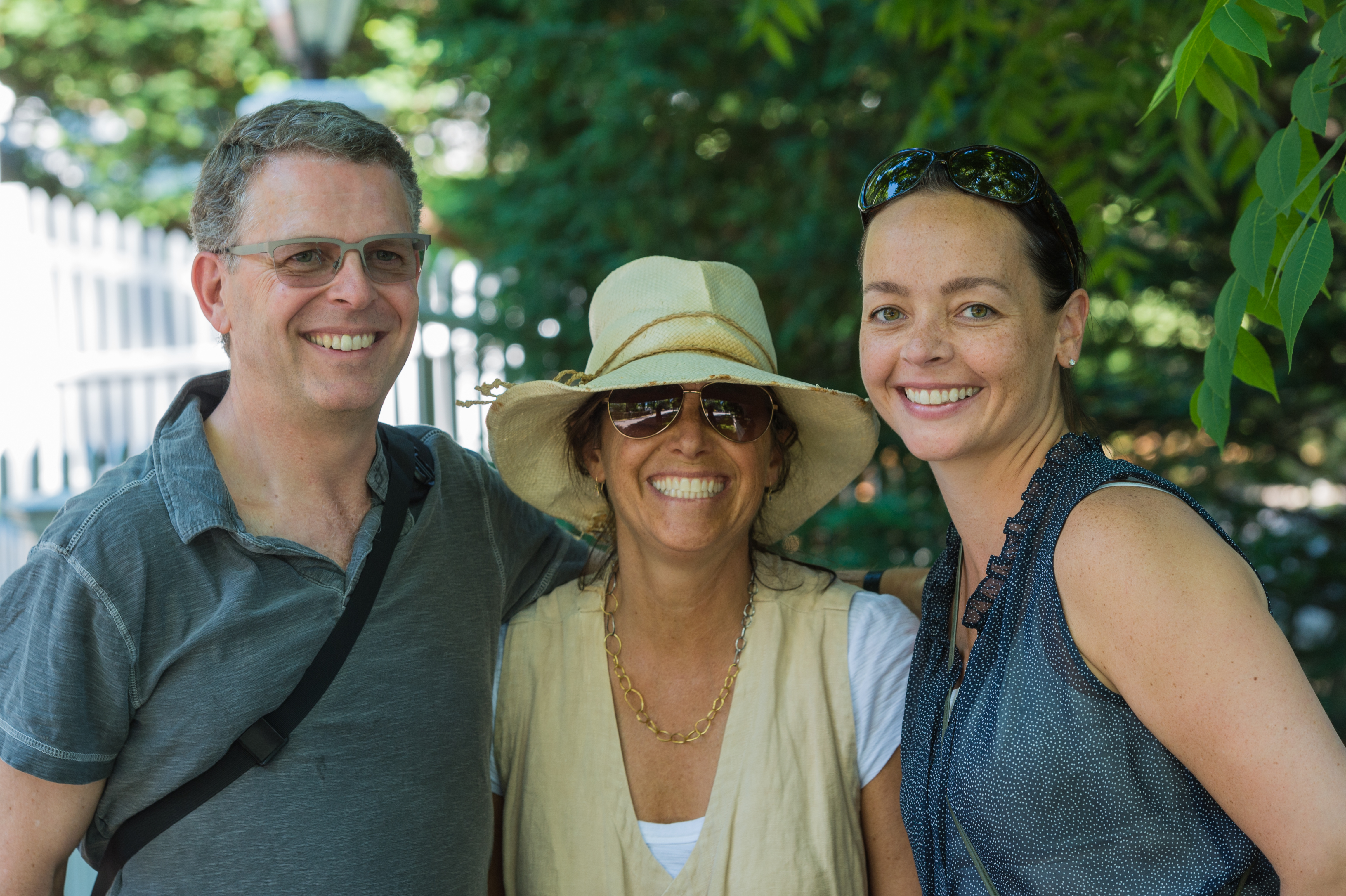 Three friends smiling together outdoors on the 4th of July.