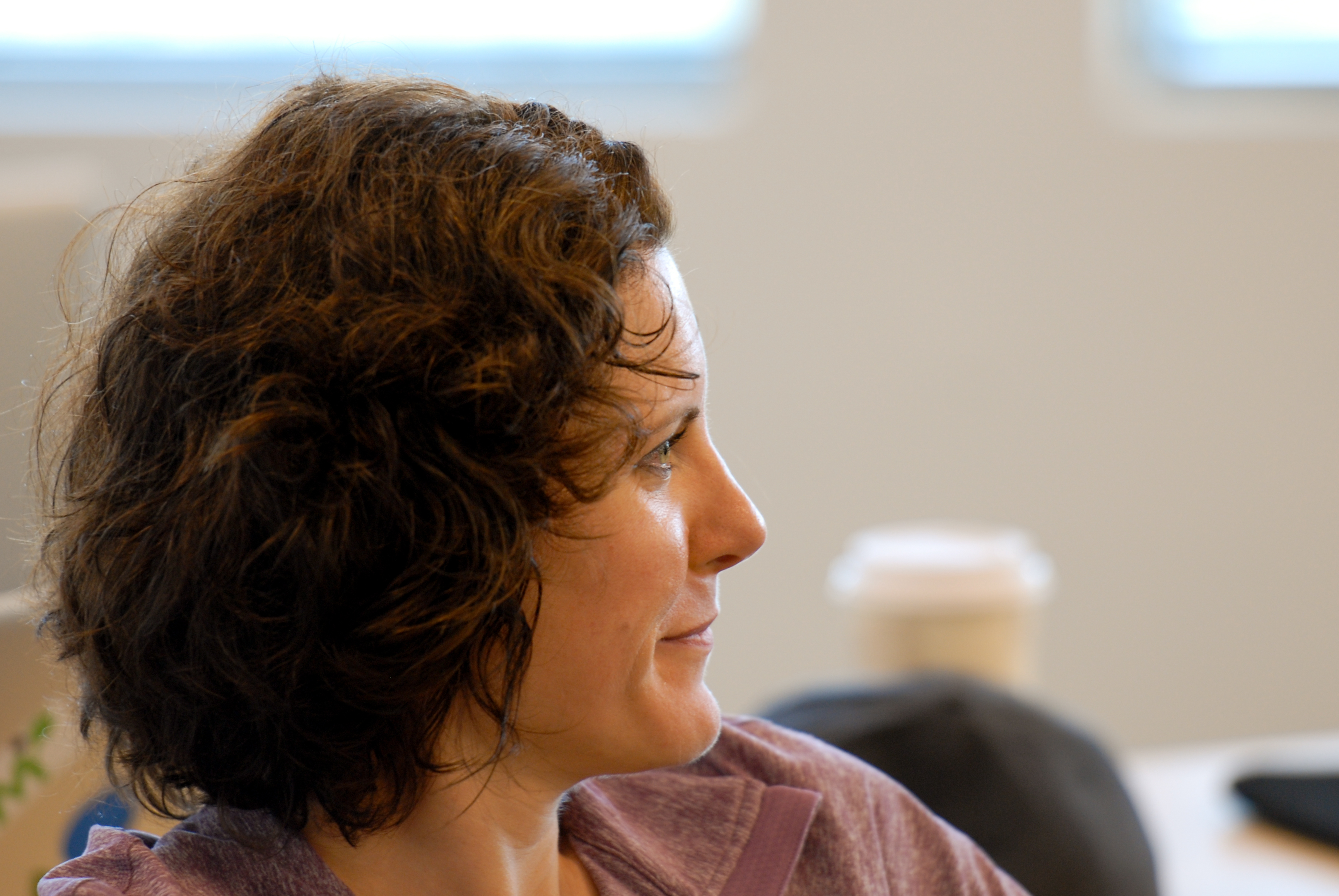 A person with short, curly hair listens attentively during a meeting or discussion.