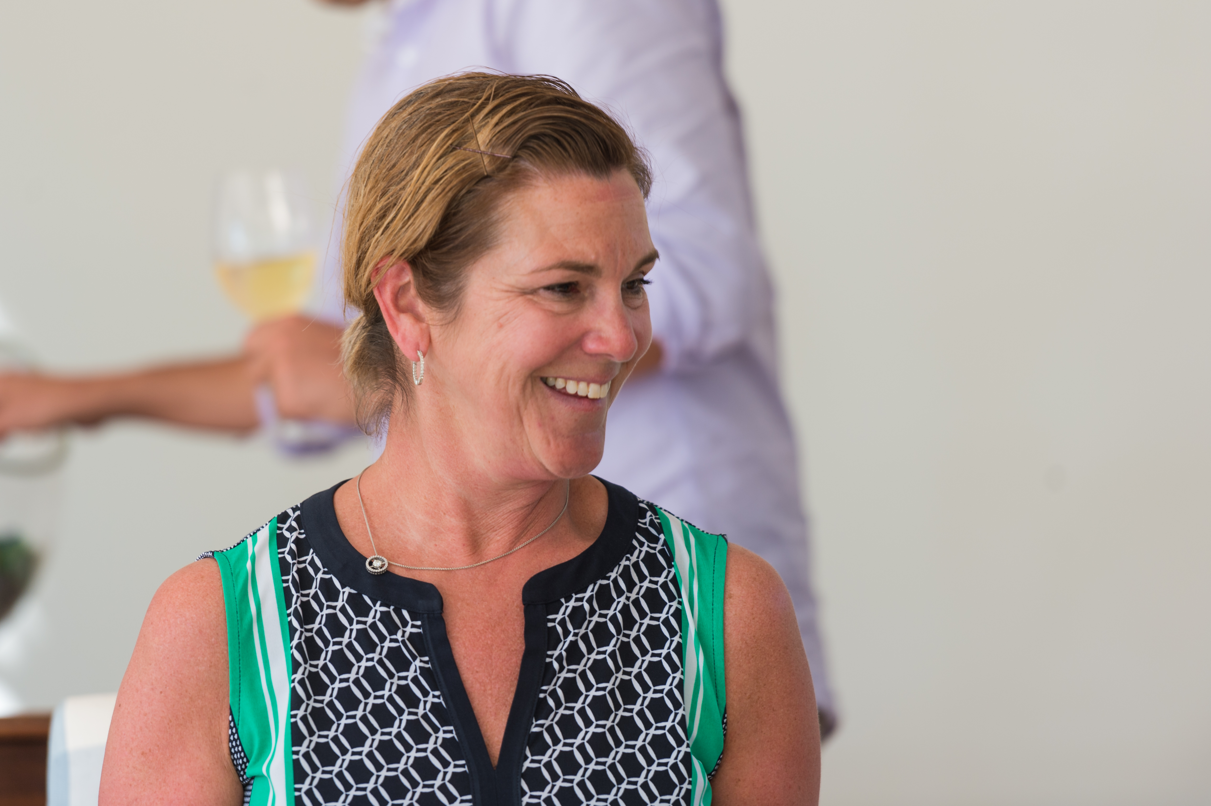A woman smiles while engaged in conversation at an offsite event.