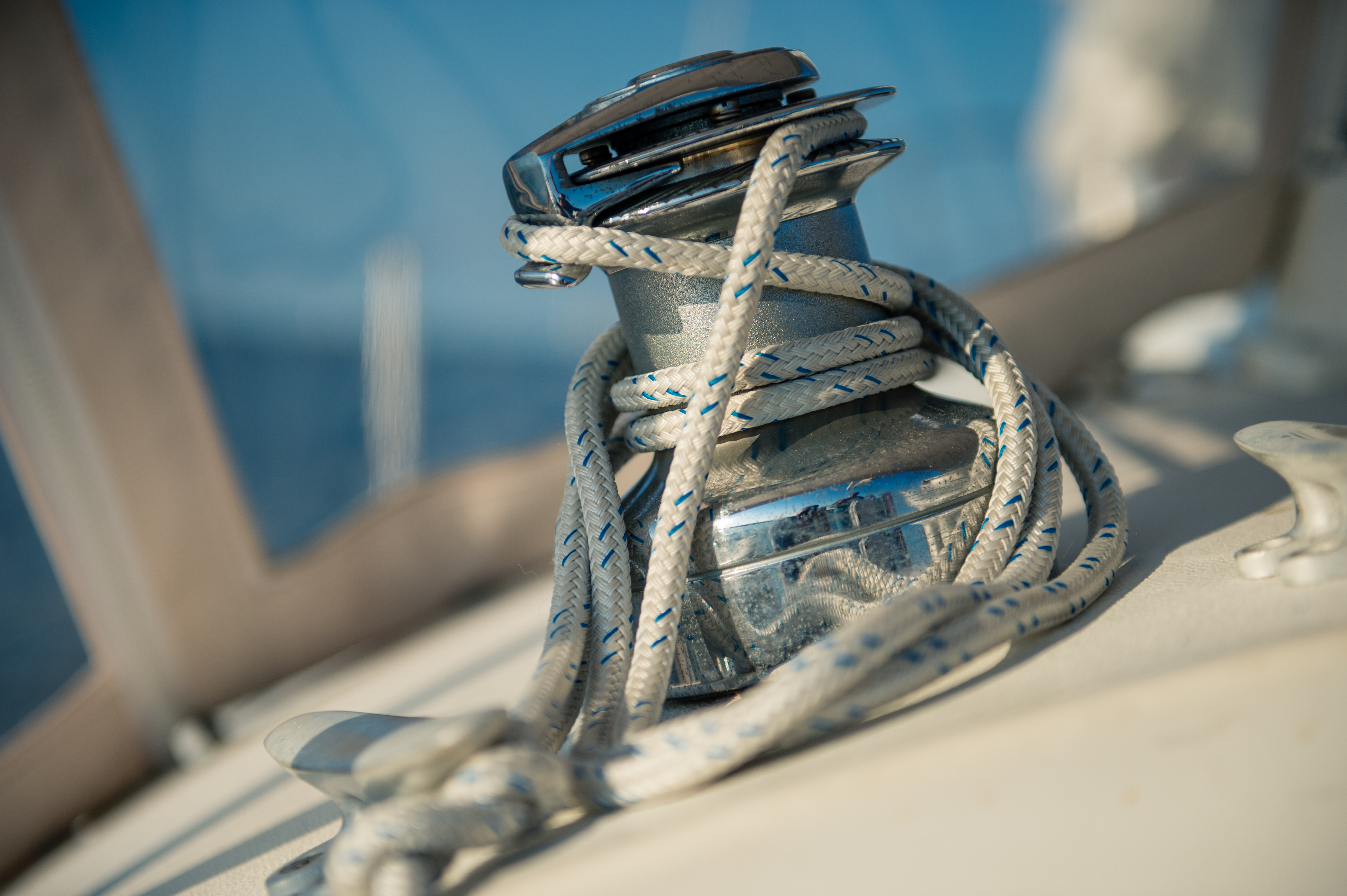 A close-up of a winch with a coiled rope on a sailboat, taken during daytime.