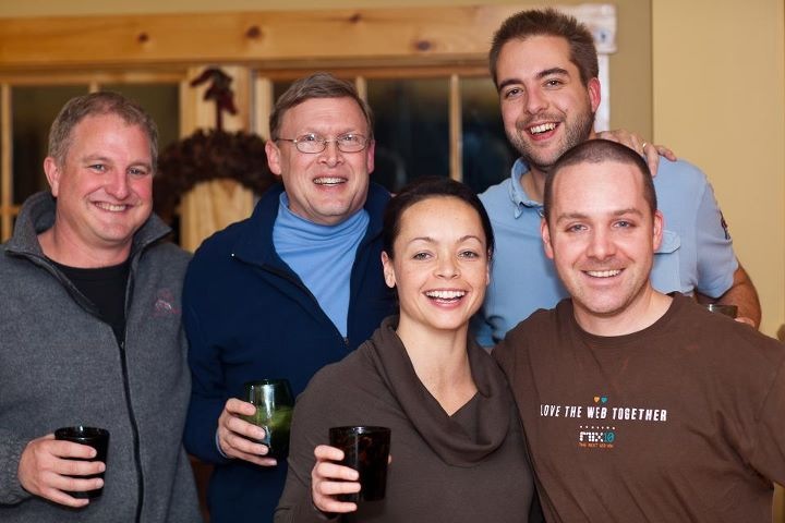 Five people smiling and holding drinks, posing together at an Acquia offsite event.